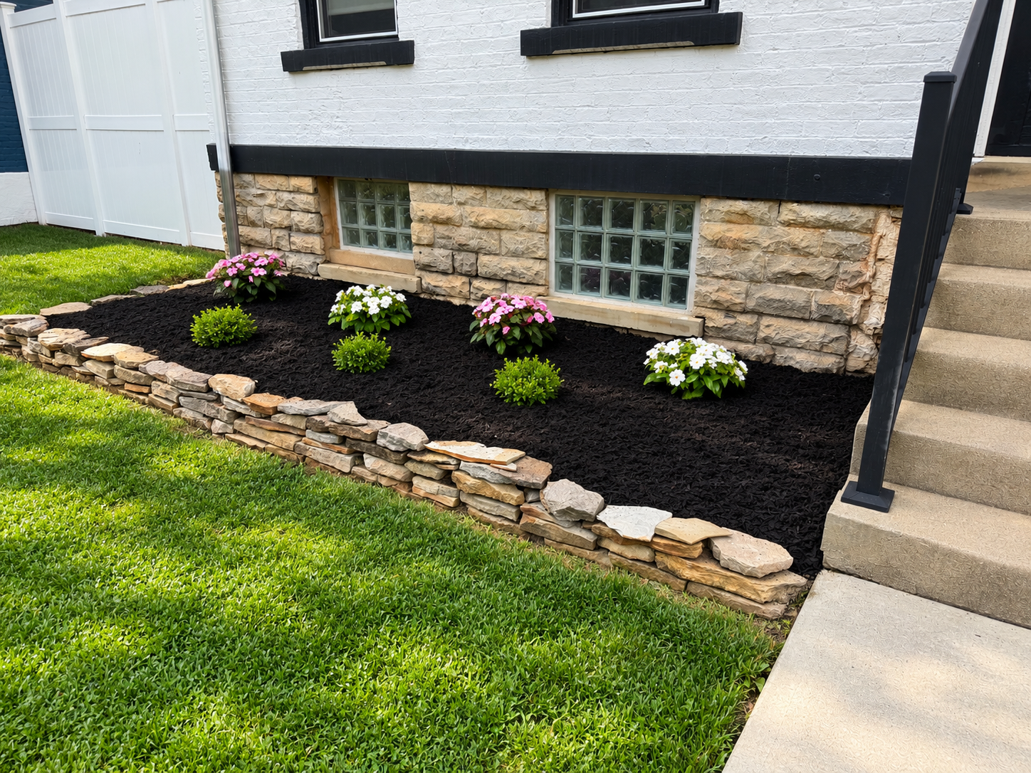 Mulch bed with natural stone border and flowering plants